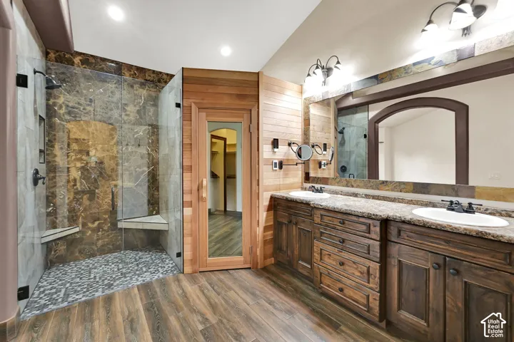 Spacious bathroom featuring a frameless glass shower enclosure with marble-patterned tile, dual built-in shower benches, and a pebble-tiled floor