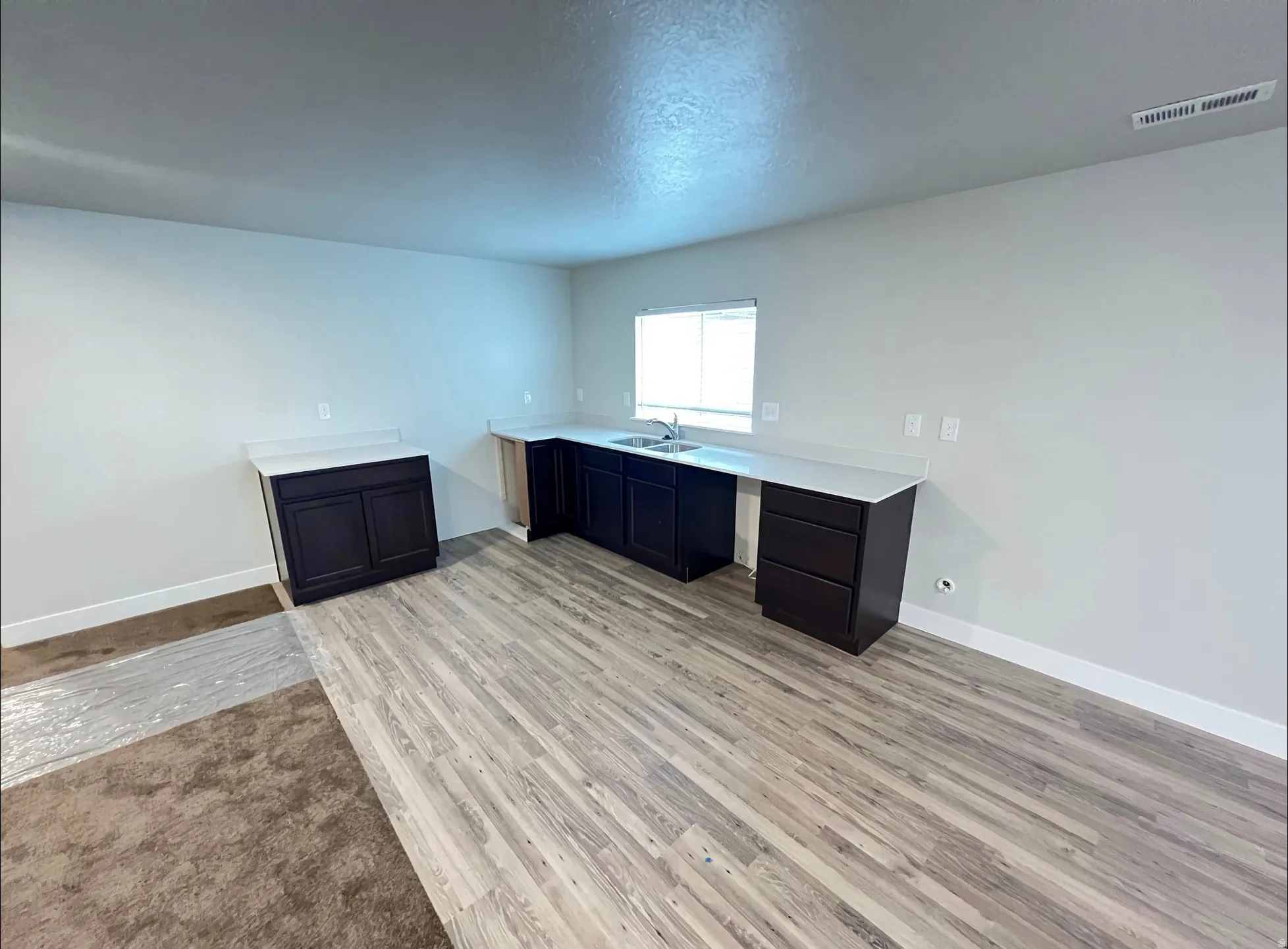 Spacious area featuring light wood-finish flooring and a partial carpeted section