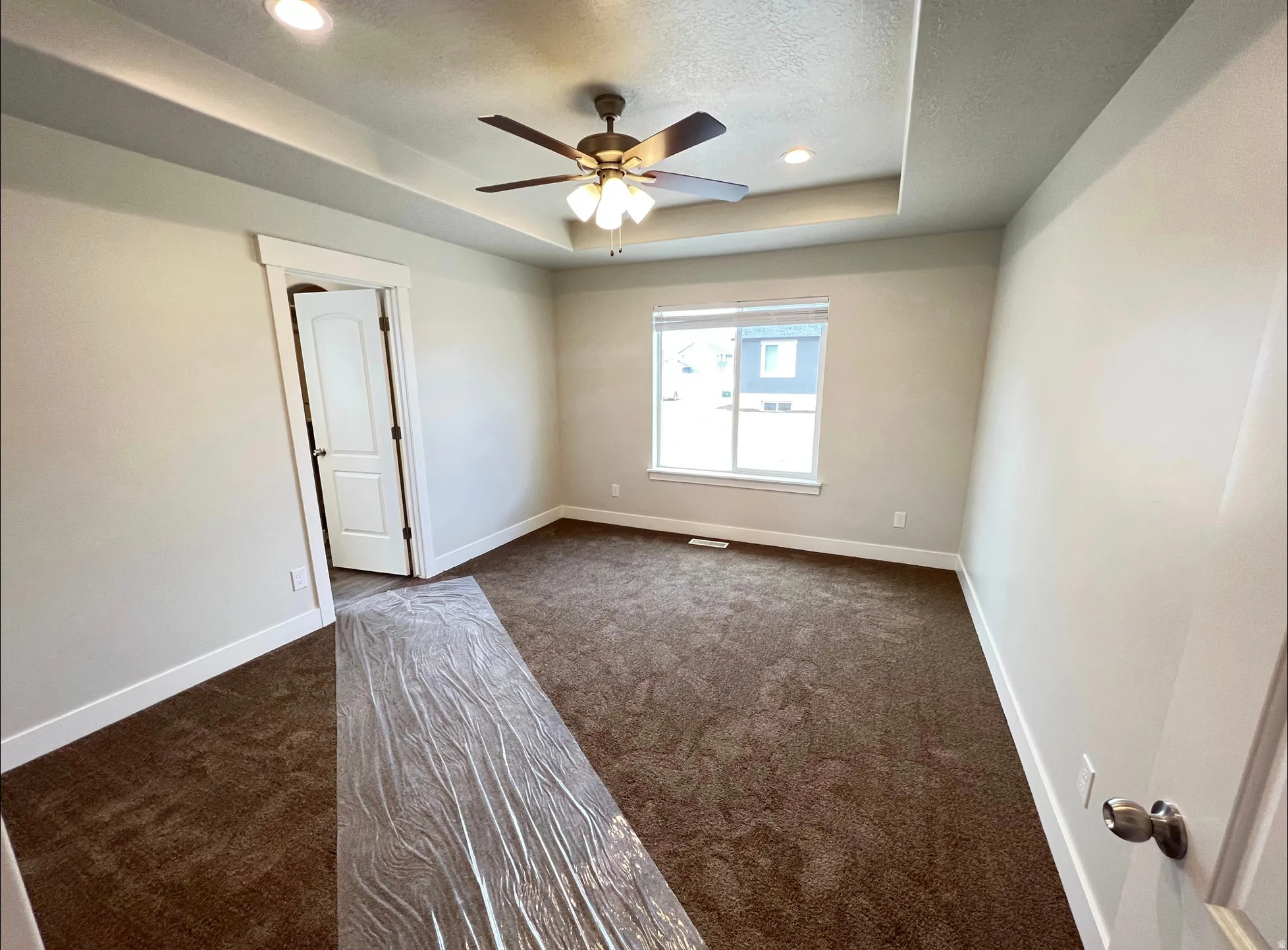 Spacious room featuring tray ceiling with recessed lighting, ceiling fan, and carpet flooring