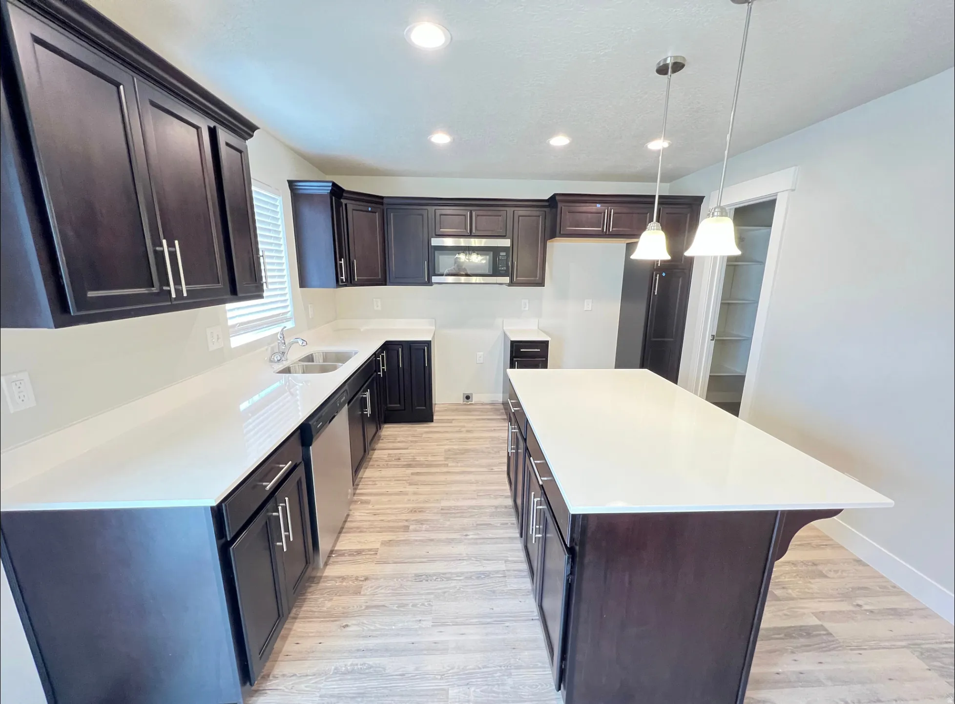 Kitchen with dark wood cabinetry, light countertops, and wood-finish flooring