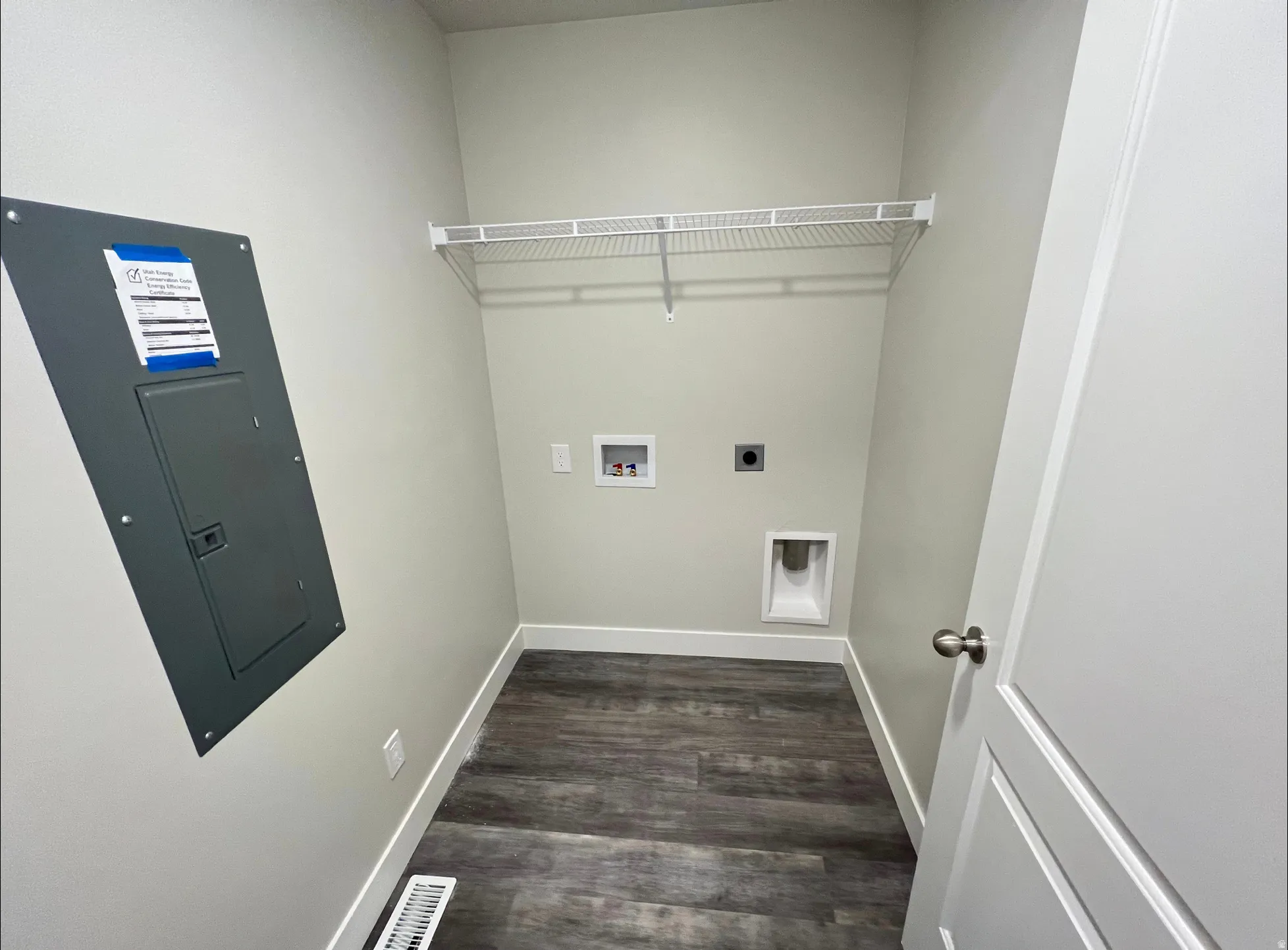 Utility area featuring wood-finish flooring, light gray walls, and white baseboards