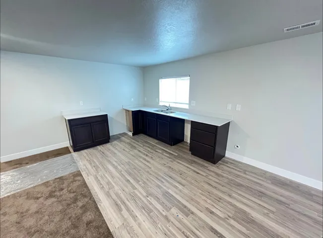 Spacious area featuring light wood-finish flooring and a partial carpeted section