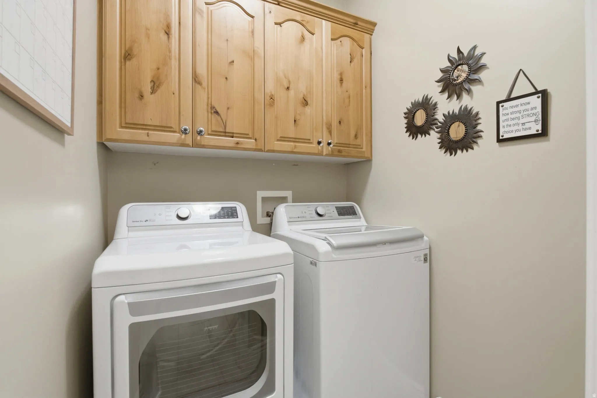 Laundry area featuring neutral wall paint, wood upper cabinetry with silver-tone hardware, and utility hookups