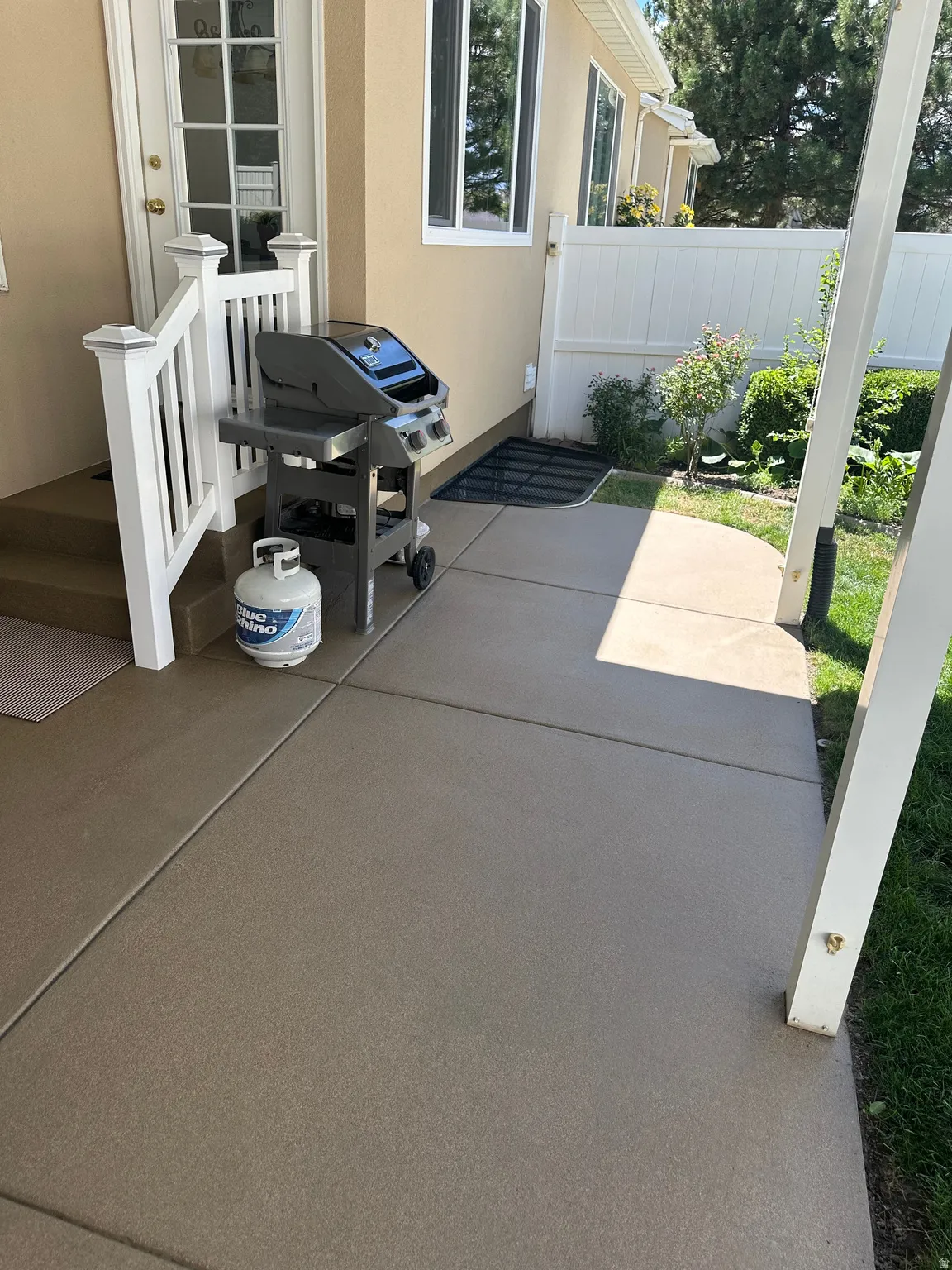 Patio access via a glass-paneled door, bordered by white railings and a privacy fence