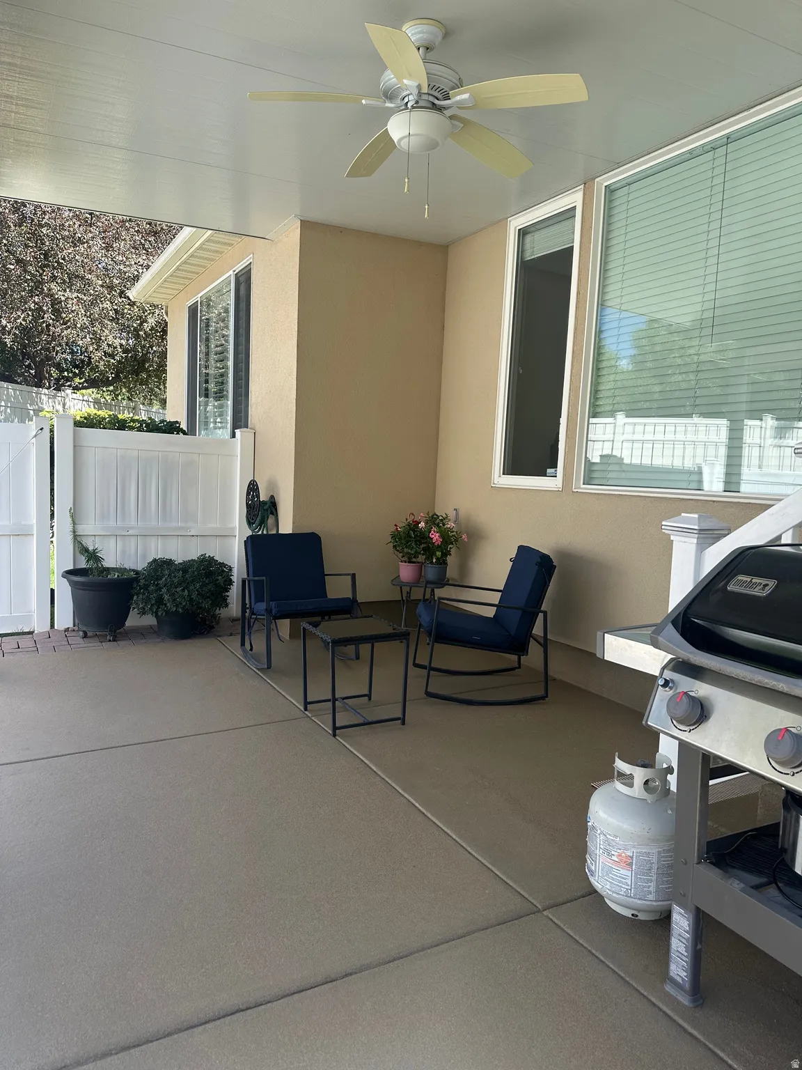 Covered patio with a ceiling fan, concrete flooring, and an exterior wall