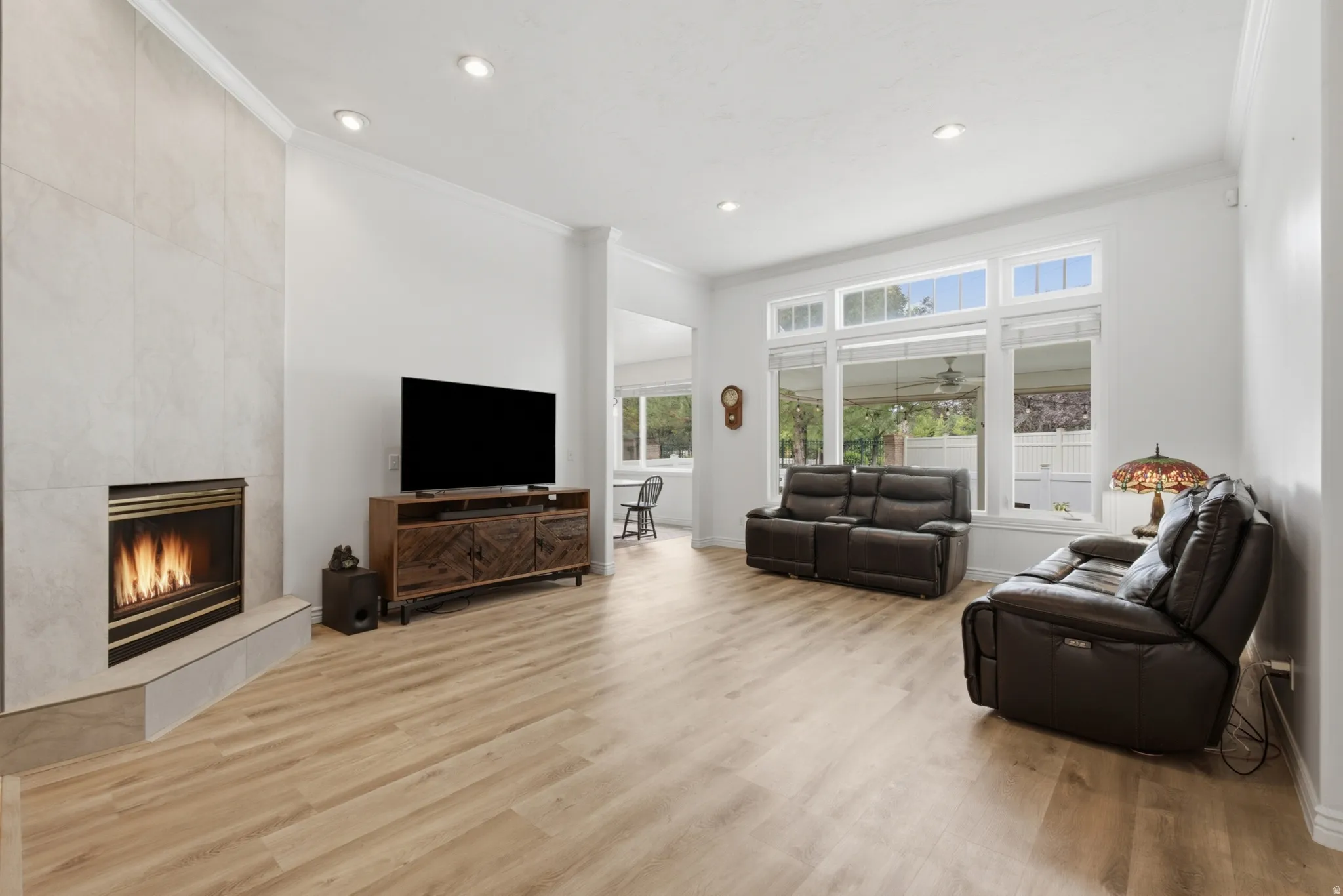 Spacious living area featuring a tile-surround fireplace with a hearth, wood-finish flooring, recessed lighting, and large windows with transom details