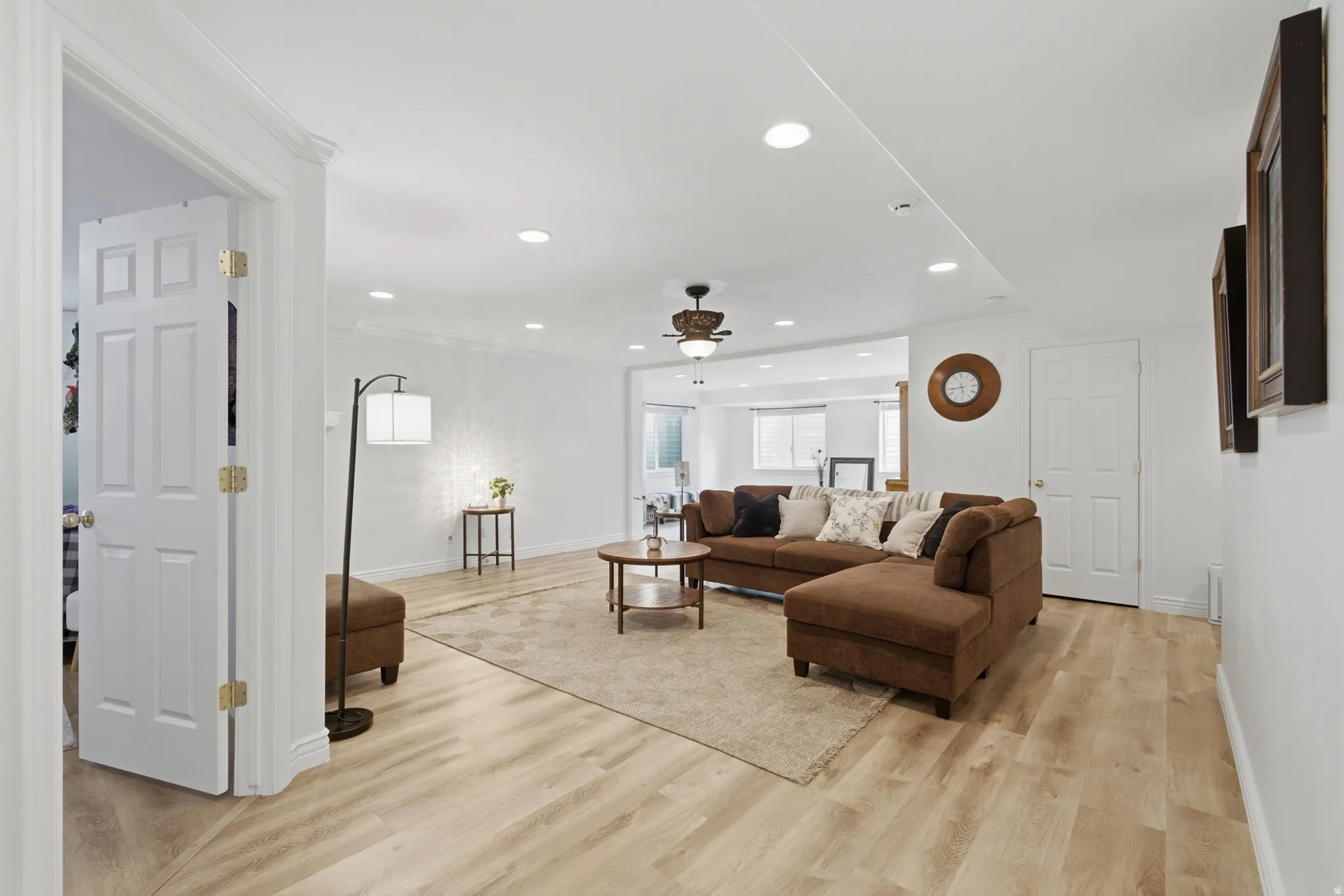 Spacious living area featuring light wood-finish flooring, recessed lighting, and a ceiling fan