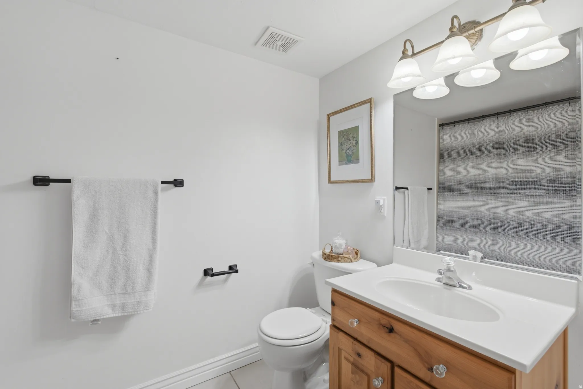 Bathroom featuring a wood-finish vanity with an integrated sink, white countertop, and a large mirror