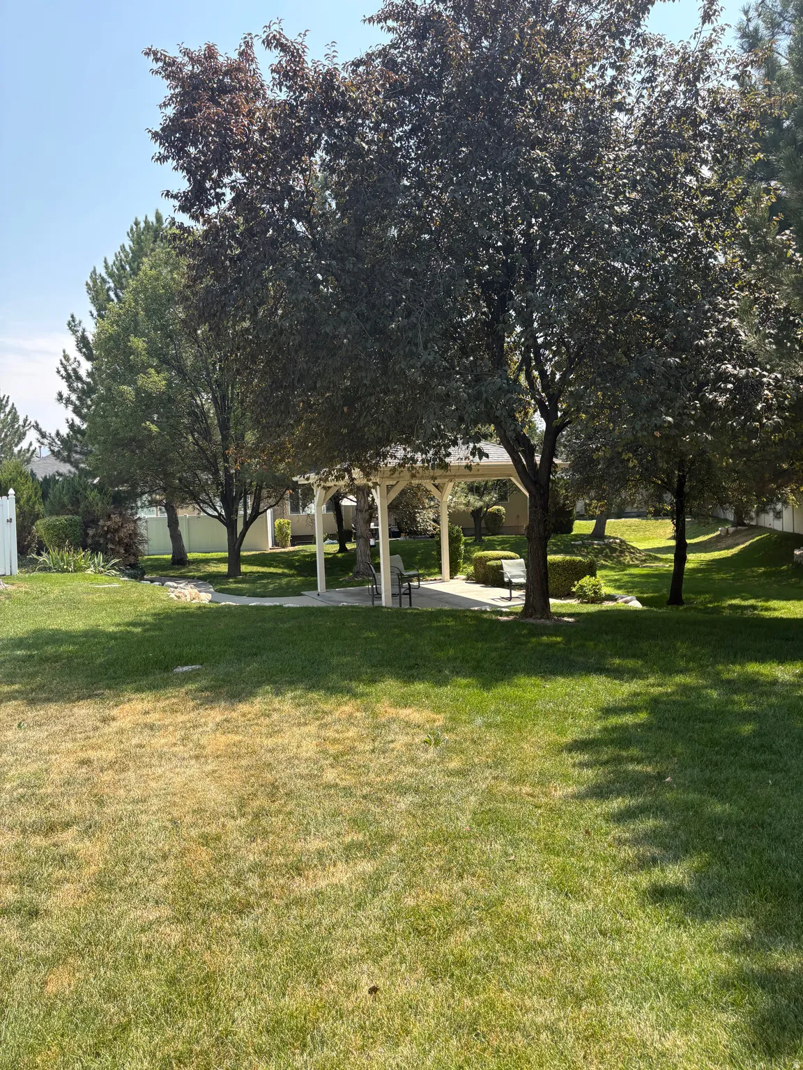 Manicured lawn with mature trees and a white gazebo