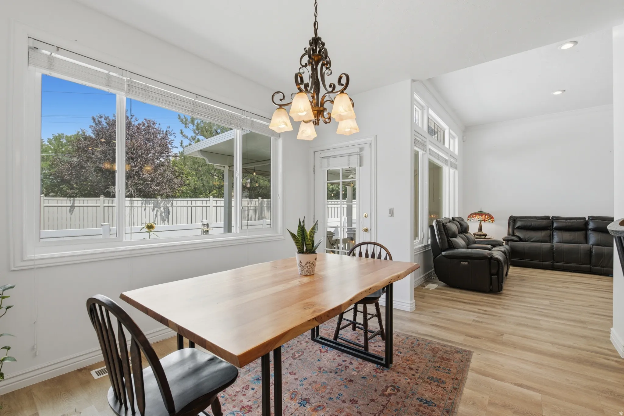 Bright dining area featuring a large picture window, a decorative chandelier, and wood-finish flooring