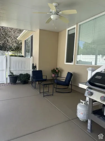 Covered patio with a ceiling fan, concrete flooring, and an exterior wall