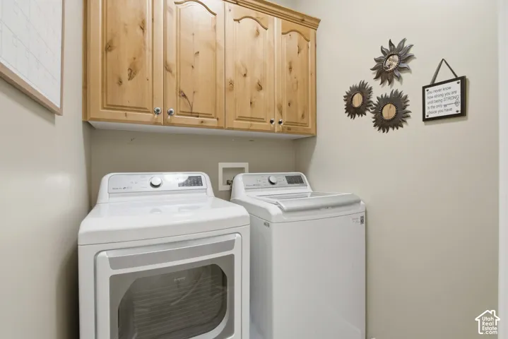Laundry area featuring neutral wall paint, wood upper cabinetry with silver-tone hardware, and utility hookups