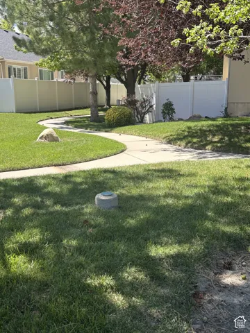 Walking trail pathway, established trees, privacy fencing, manicured lawn, and natural stone accent