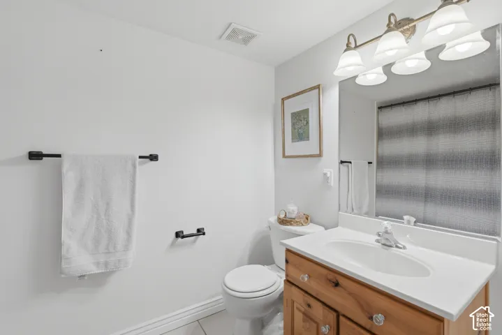 Bathroom featuring a wood-finish vanity with an integrated sink, white countertop, and a large mirror