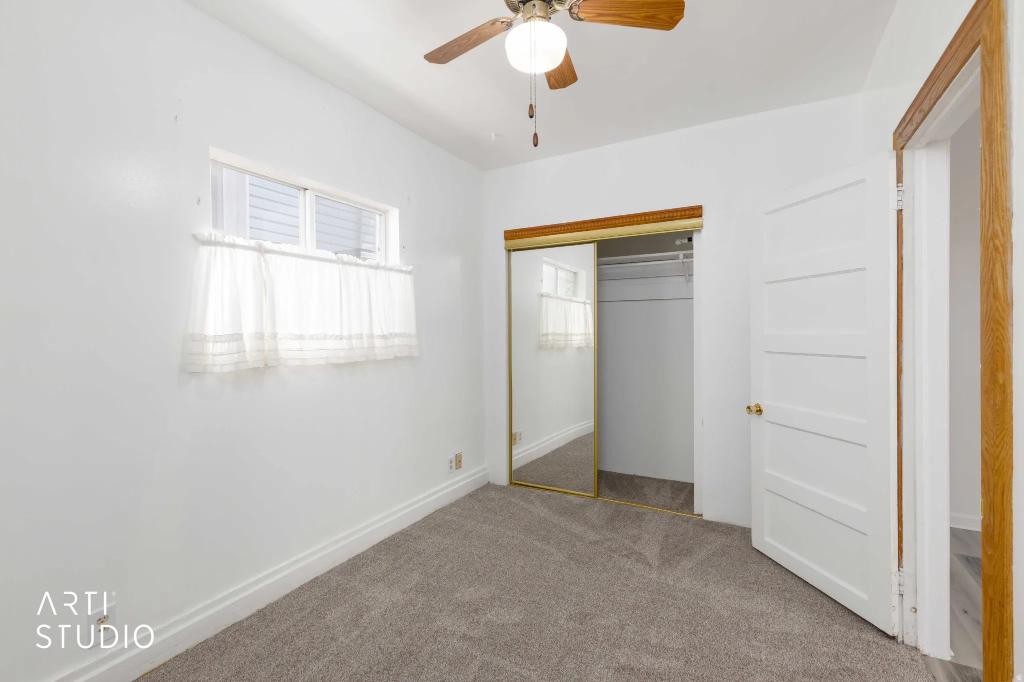 Light grey carpeted flooring, white walls, and a ceiling fan with light fixture