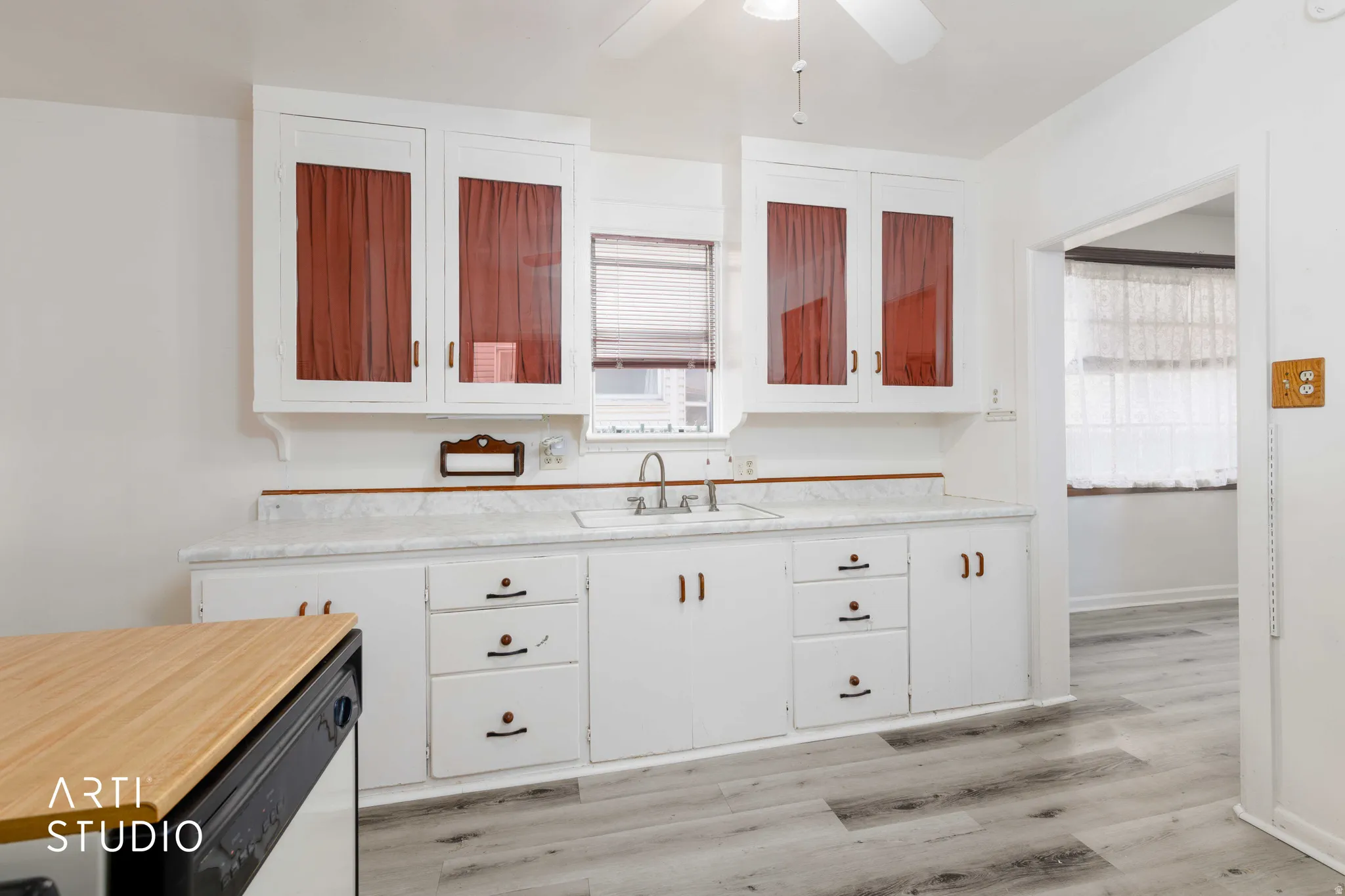 White cabinetry with glass-front upper cabinets, white countertop, single basin sink with chrome faucet, and wood-finish flooring