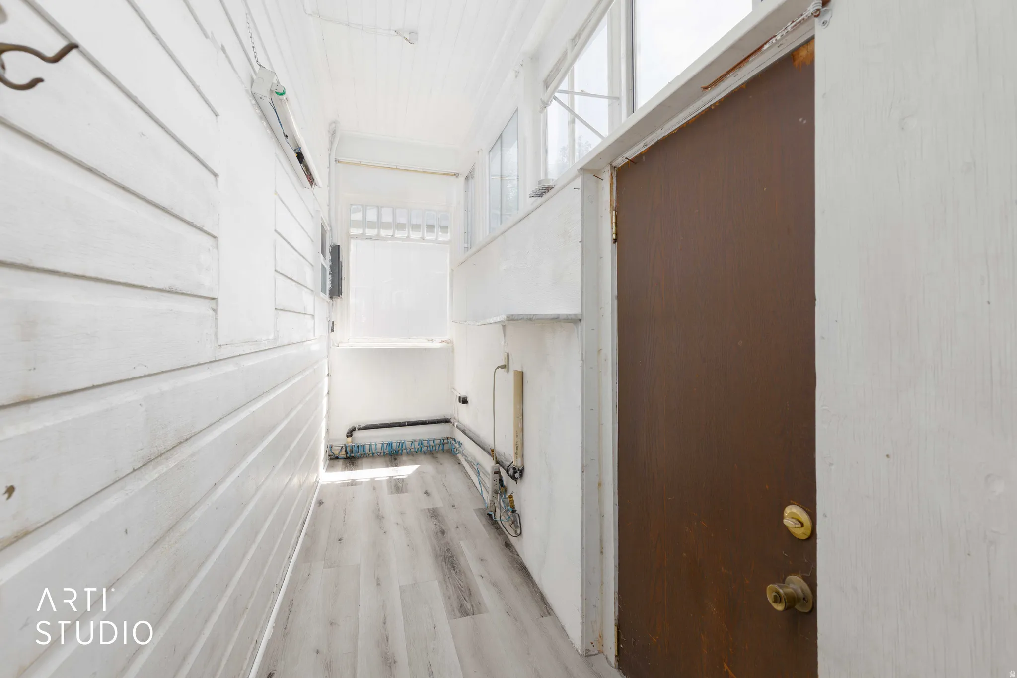 Wood-finish flooring with white paneled walls and a brown entry door