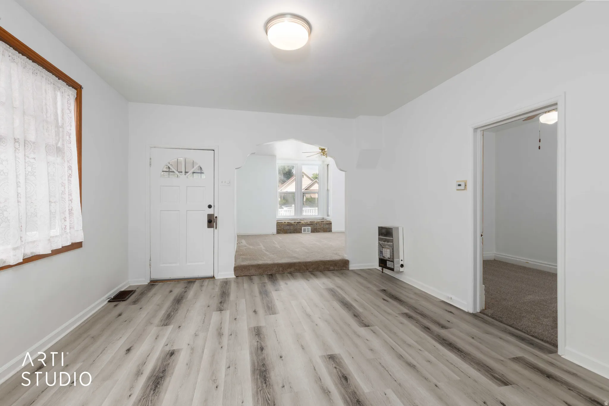 Wood-finish flooring, white walls, and a recessed archway define this interior space