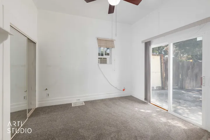 Carpeted flooring, mirrored sliding closet doors, window with horizontal blinds, and a ceiling fan