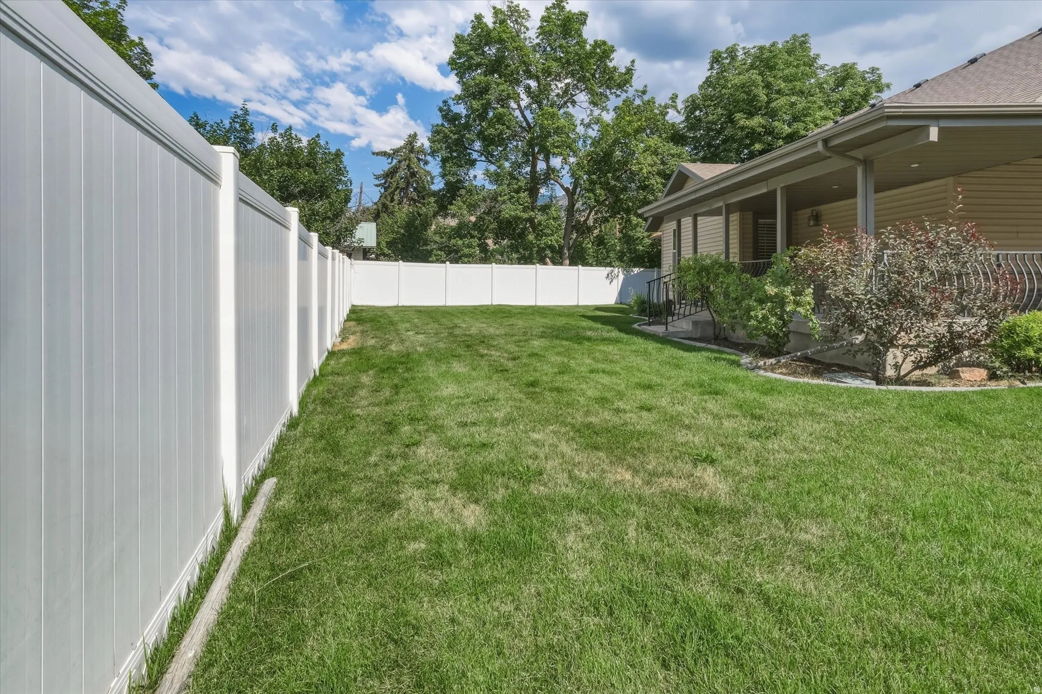 Expansive green lawn fully enclosed by a white privacy fence