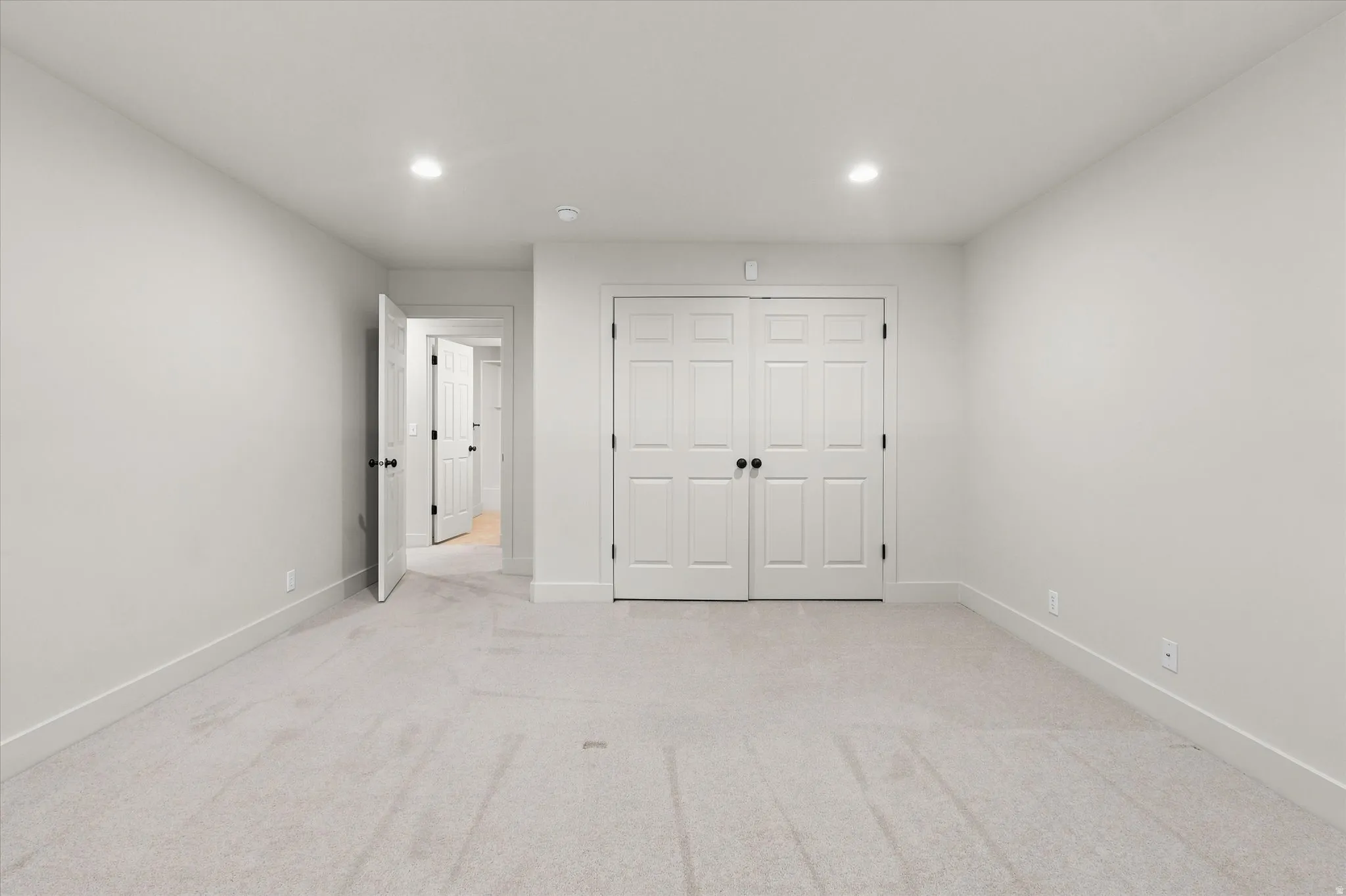 Neutral-toned room featuring light gray carpet flooring and white baseboards