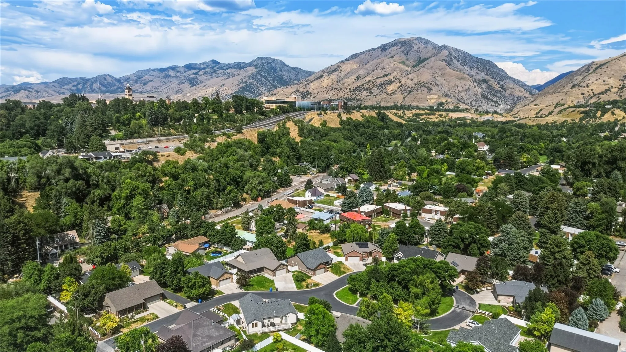 Expansive residential area featuring established homes with mature landscaping, surrounded by verdant trees and mountainous terrain