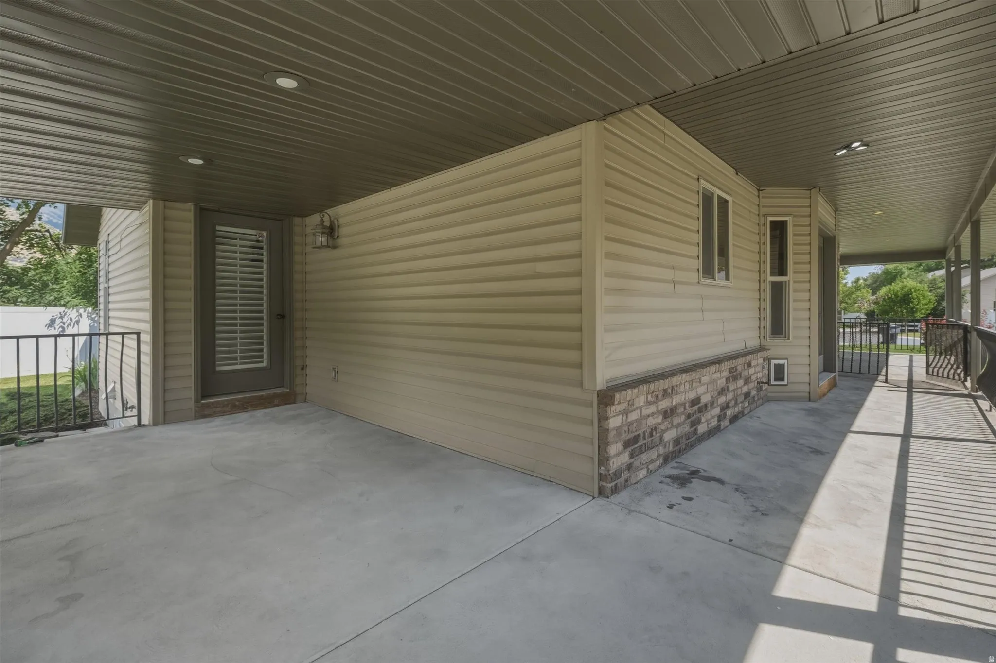 Covered concrete patio with recessed lighting and a privacy screen door