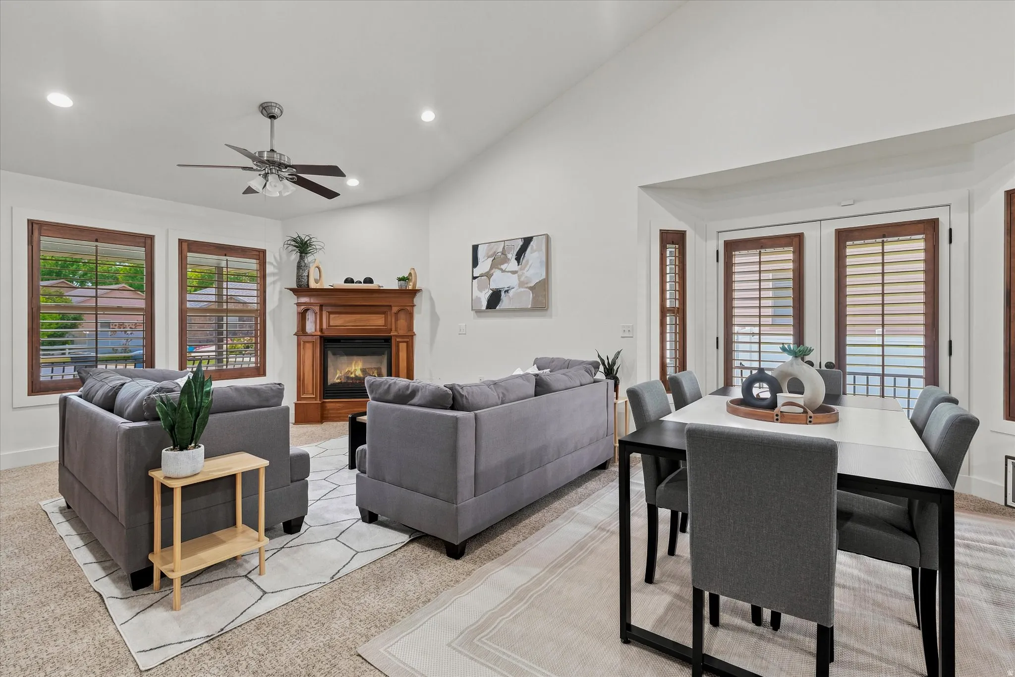 Vaulted ceiling great room featuring a wood-mantled fireplace, recessed lighting, and a ceiling fan
