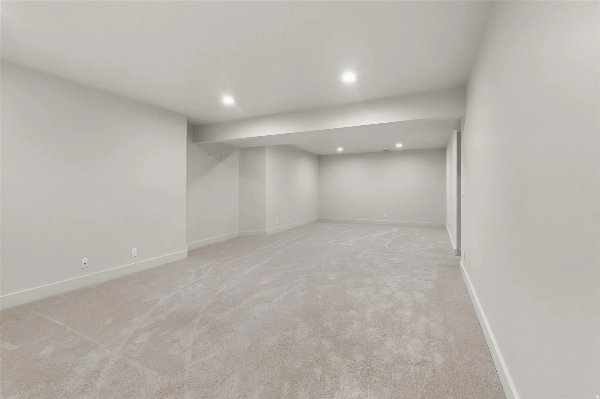 Spacious room featuring light-colored carpeting and recessed ceiling lighting