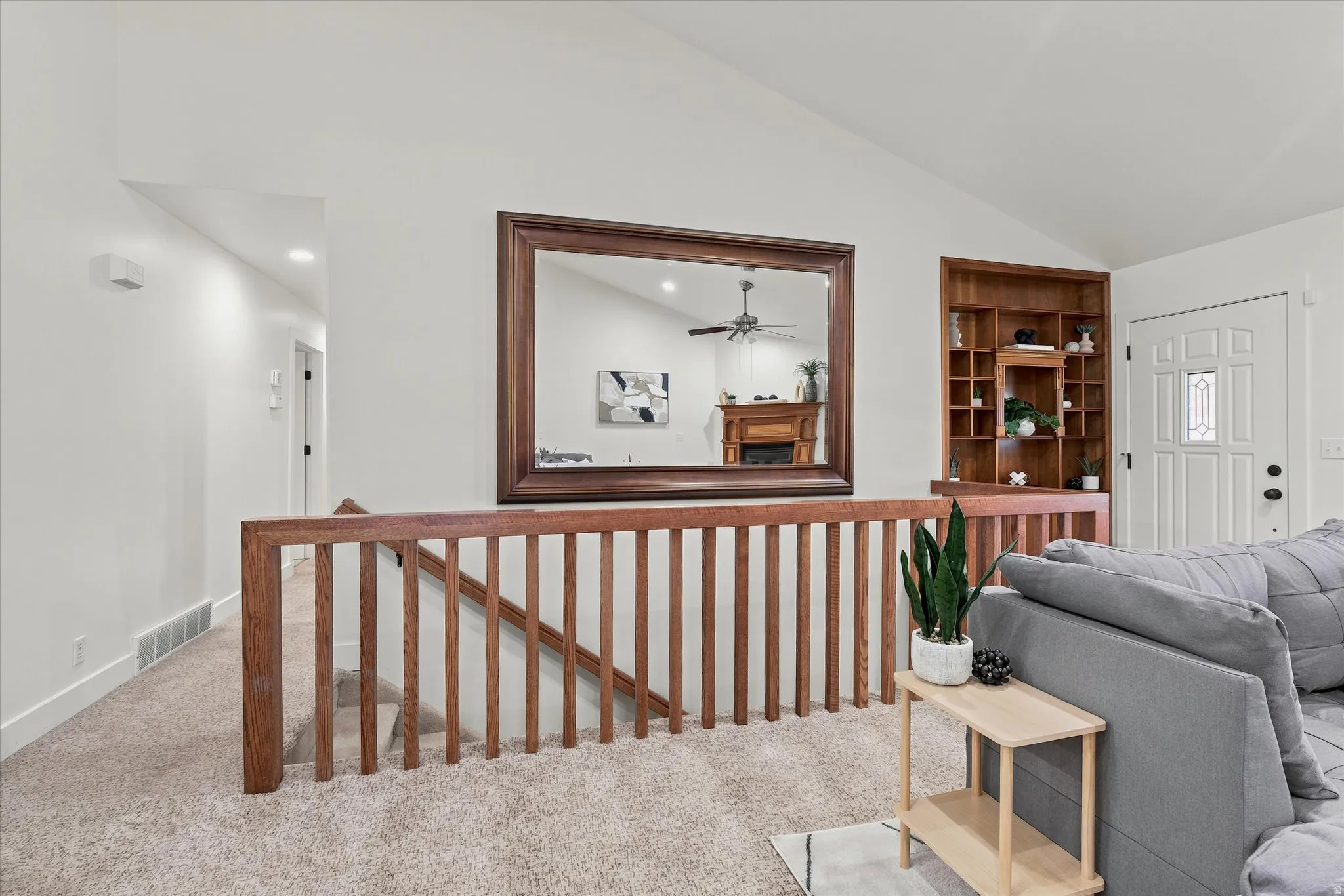 Upper-level landing featuring a wood railing and built-in shelving