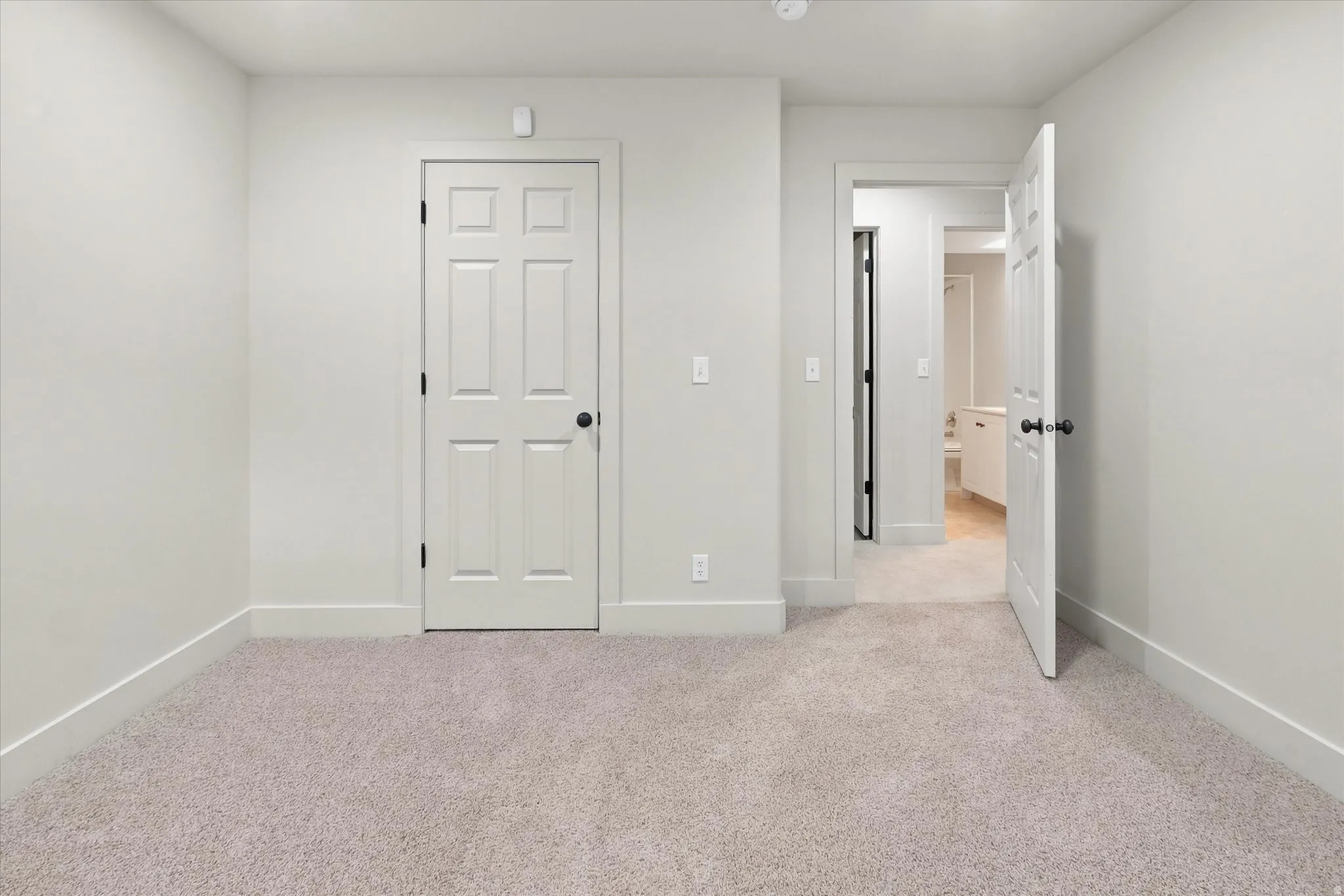 Carpeted room with a six-panel door featuring a matte black handle