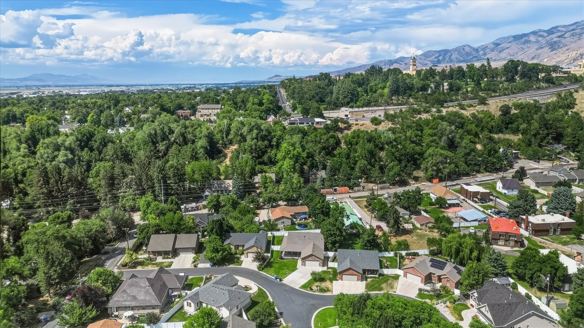 Aerial overview of a residential area featuring established homes, mature trees, and mountain backdrops