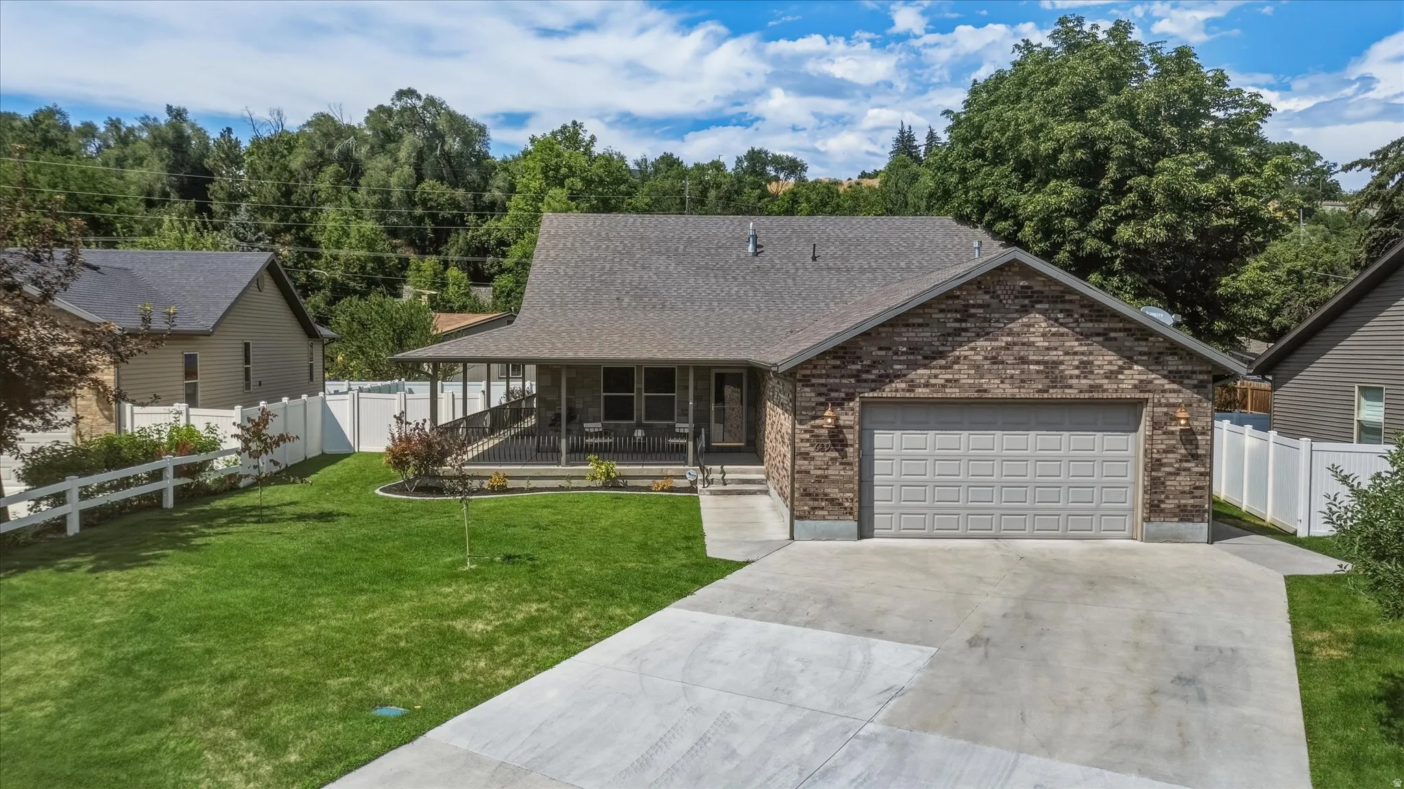 Single-story residence featuring a covered front porch, brick facade accents, an attached two-car garage, and a concrete driveway