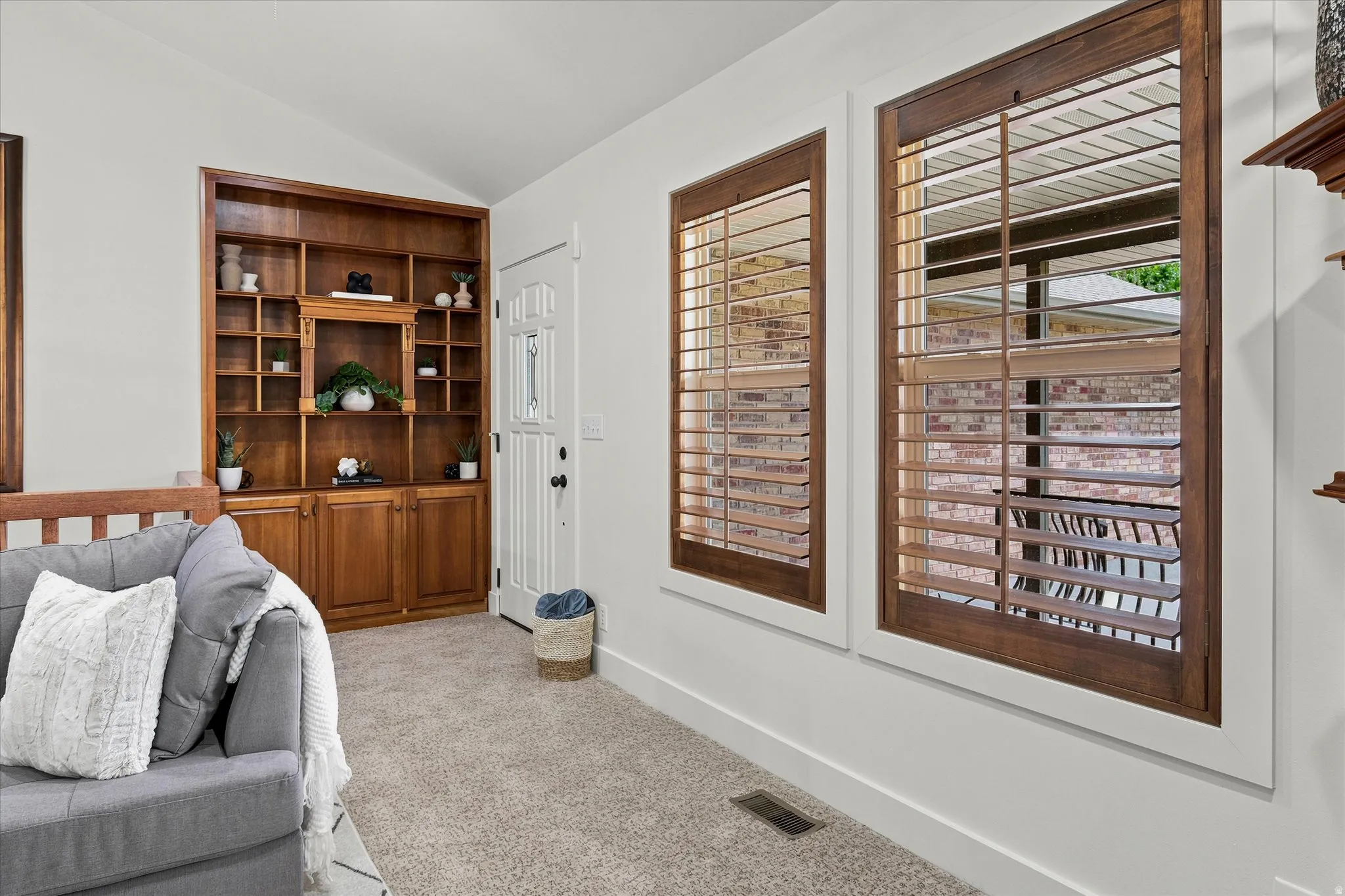 Built-in wood shelving and cabinetry complement the entry door with decorative glass