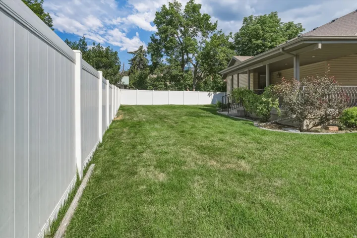 Expansive green lawn fully enclosed by a white privacy fence