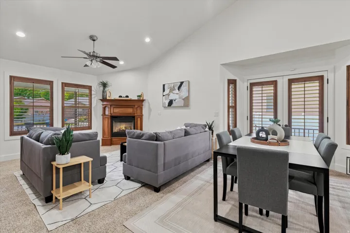 Vaulted ceiling great room featuring a wood-mantled fireplace, recessed lighting, and a ceiling fan