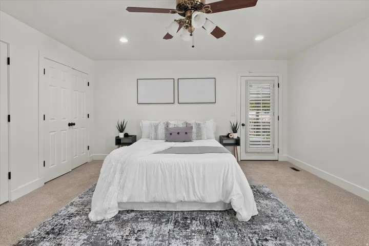 Spacious bedroom featuring neutral carpeting, a ceiling fan with integrated lighting, and recessed ceiling lights