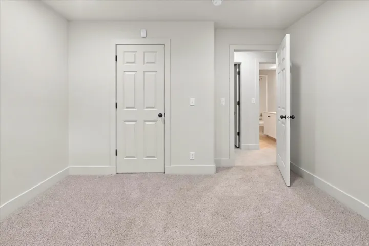 Carpeted room with a six-panel door featuring a matte black handle