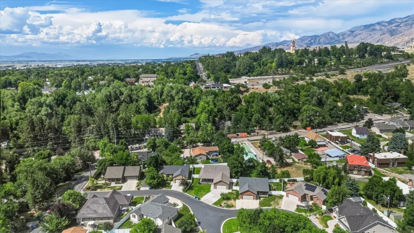 Aerial overview of a residential area featuring established homes, mature trees, and mountain backdrops
