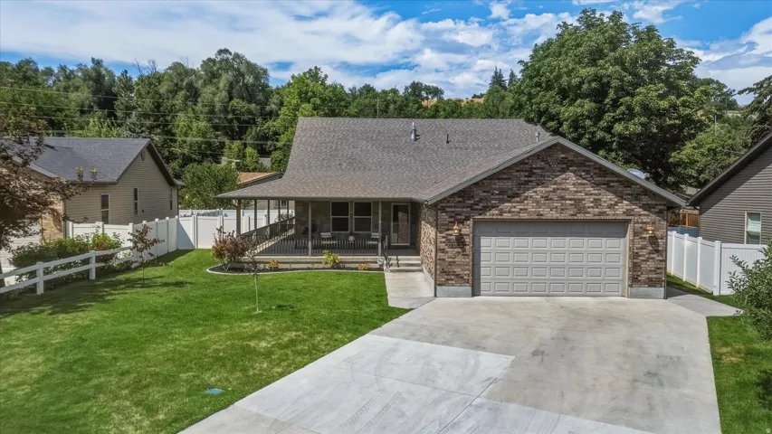 Single-story residence featuring a covered front porch, brick facade accents, an attached two-car garage, and a concrete driveway