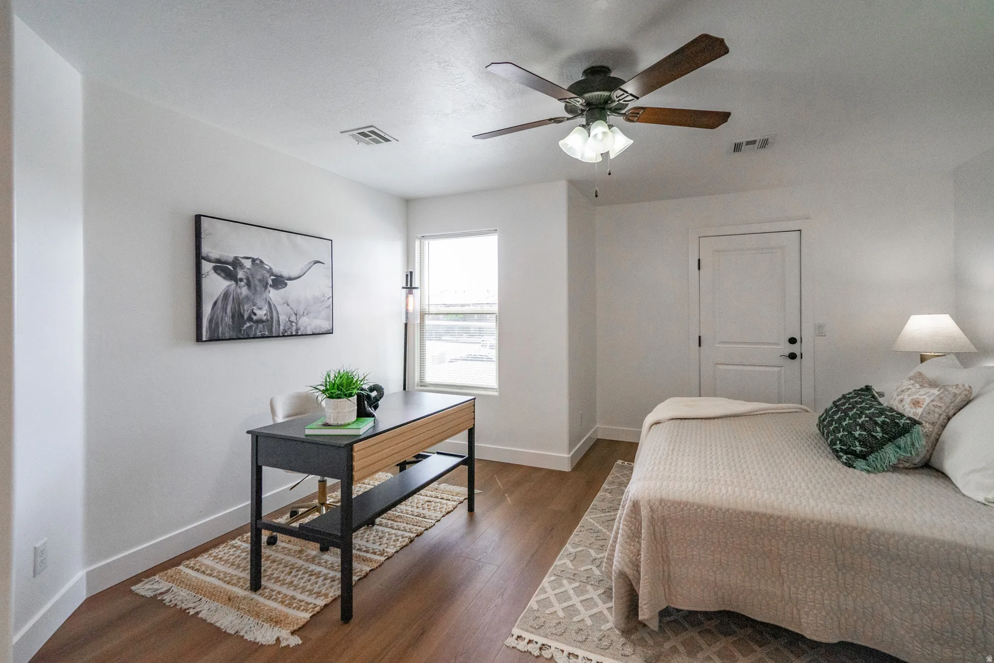 Bright interior space featuring wood-finish flooring, a ceiling fan with integrated lighting, white baseboards, a white paneled door, and a single window