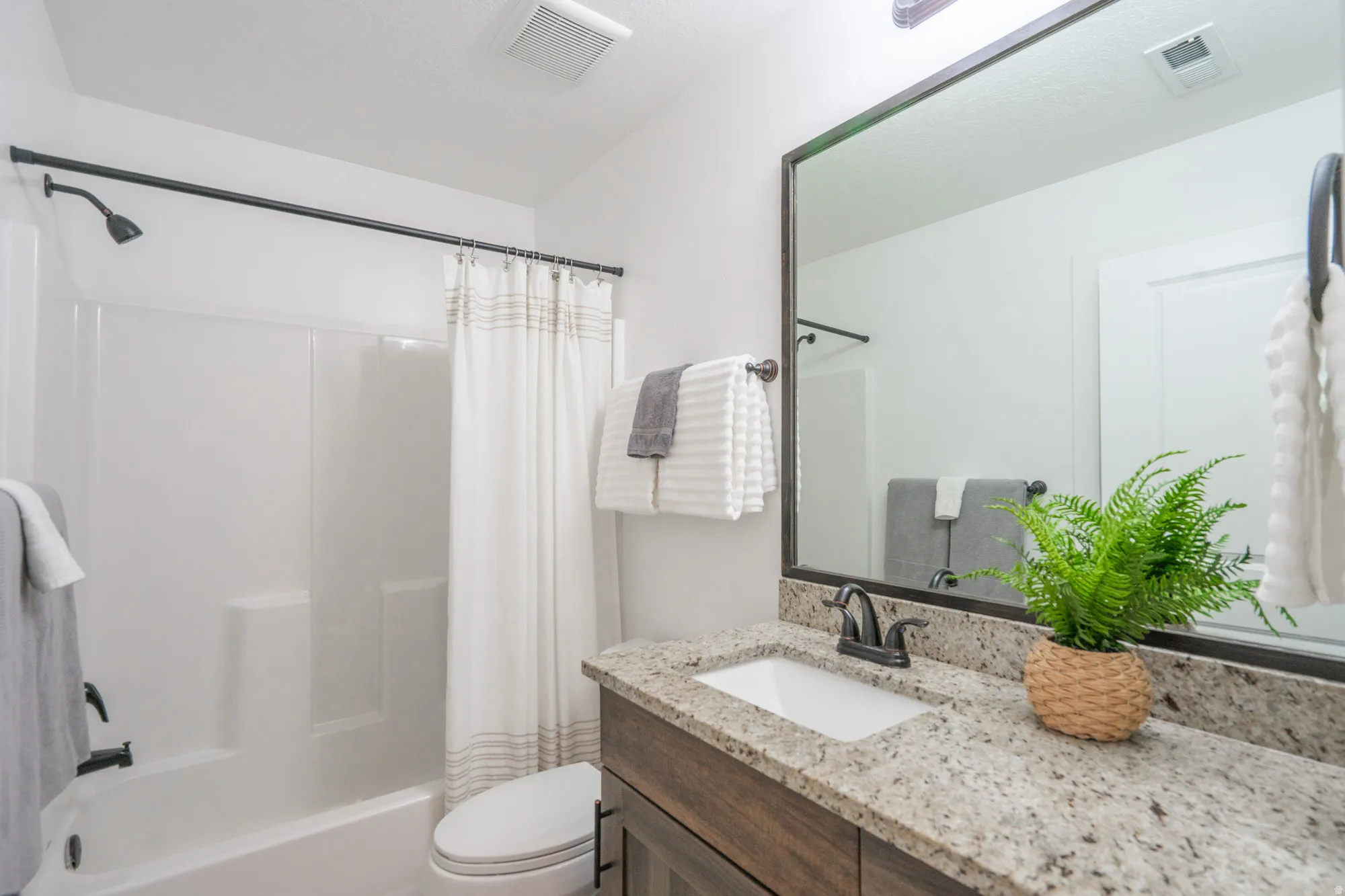 Bathroom featuring a vanity with a granite-style countertop, a rectangular undermount sink, and dark bronze fixtures
