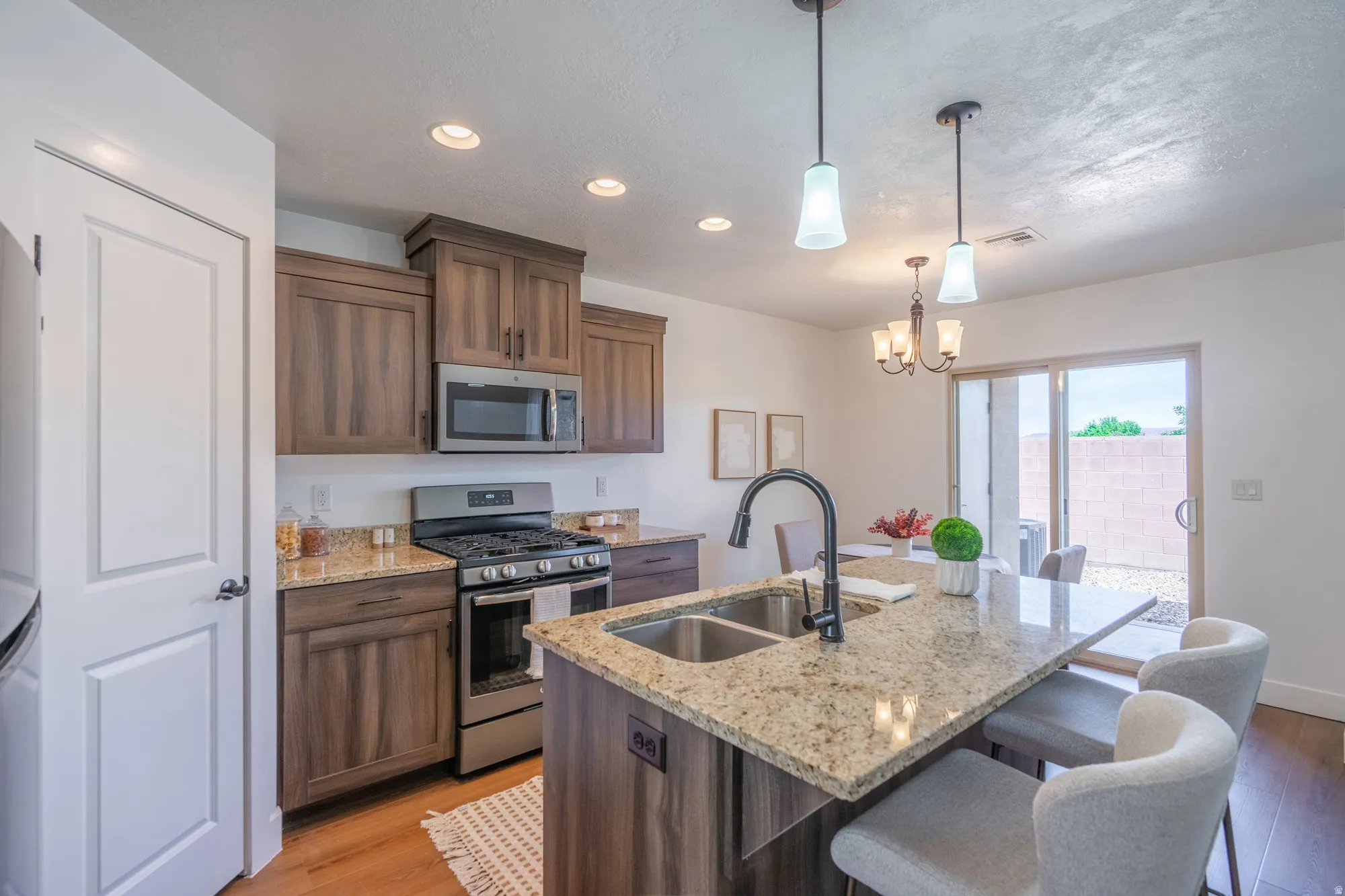 Gourmet kitchen featuring wood-finish cabinetry, stainless steel appliances, granite countertops, and a dual basin sink with a high-arch faucet