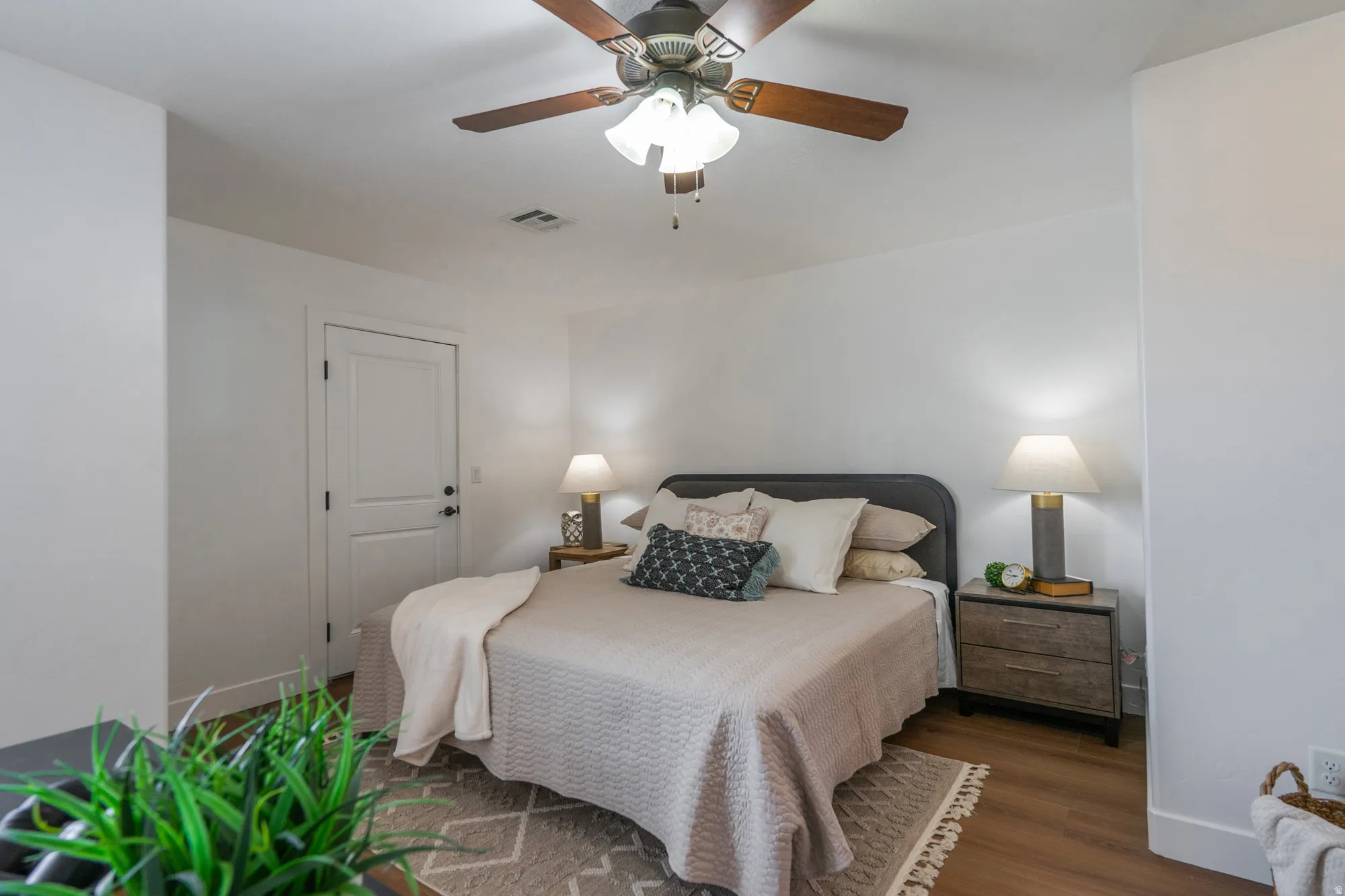 Bedroom featuring wood-finish flooring, a ceiling fan with integrated lighting, and a white paneled door