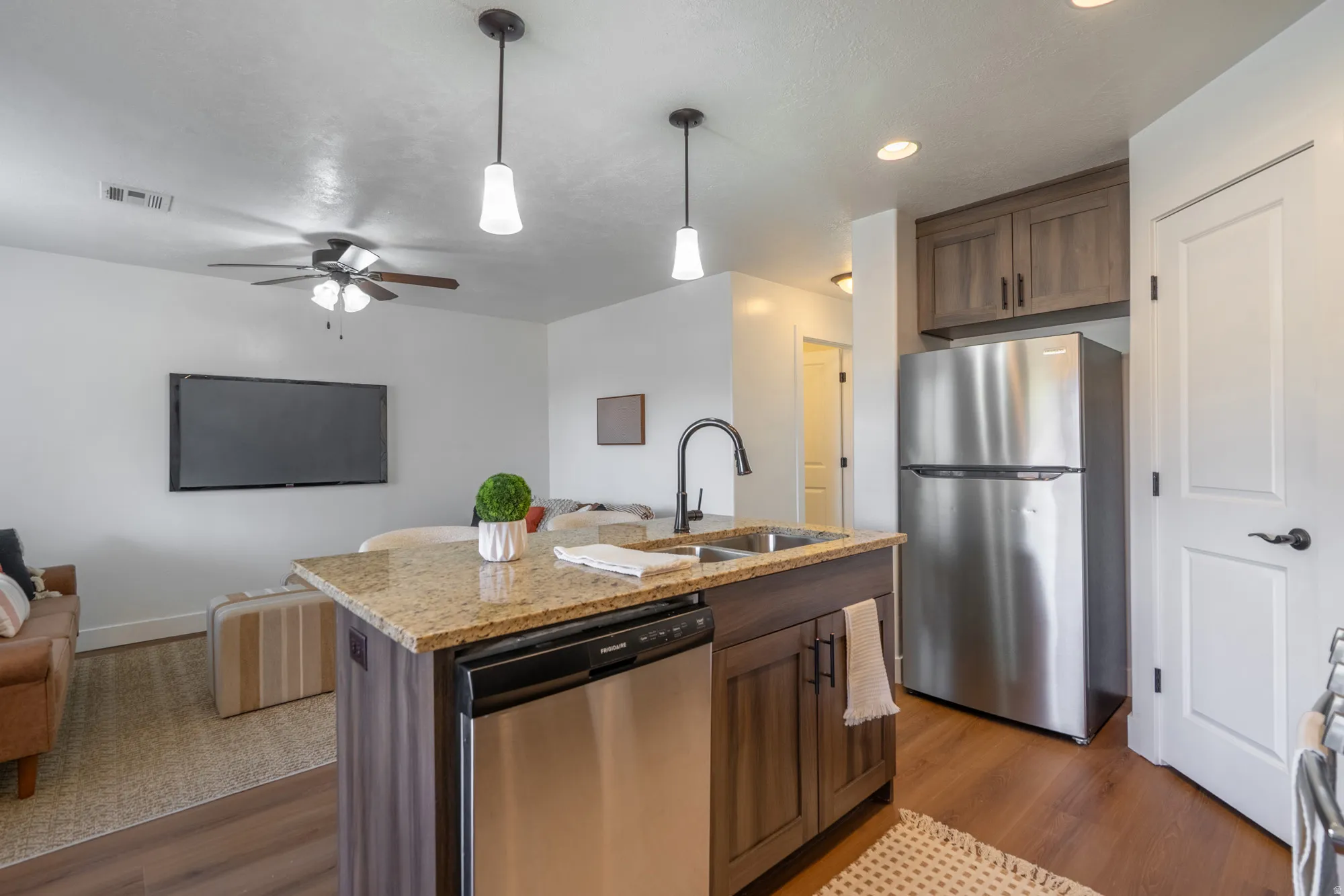 Kitchen island featuring a granite countertop, stainless steel sink with a matte black faucet, and integrated dishwasher
