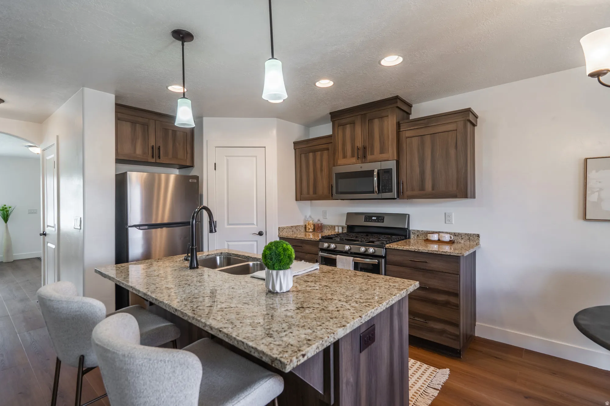 Kitchen featuring a central island with a double basin sink and granite countertop