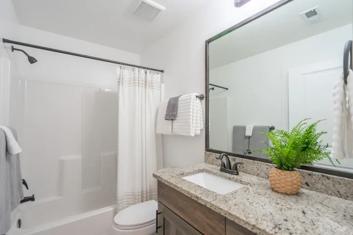Bathroom featuring a vanity with a granite-style countertop, a rectangular undermount sink, and dark bronze fixtures