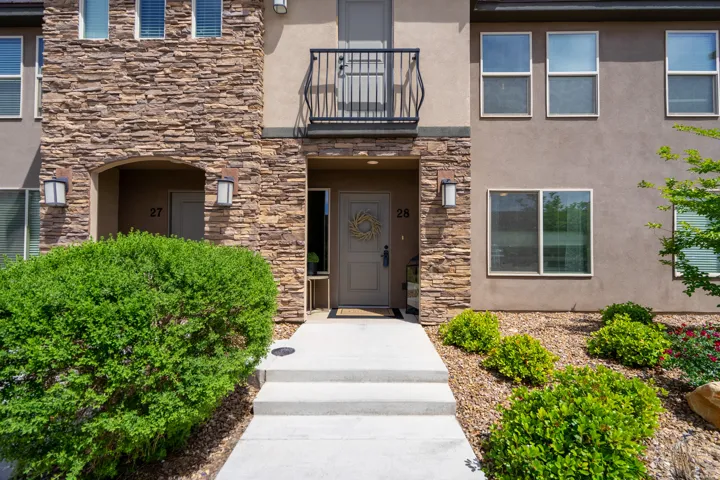 Multi-story building facade featuring stacked stone accents and a stucco finish