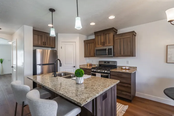 Kitchen featuring a central island with a double basin sink and granite countertop