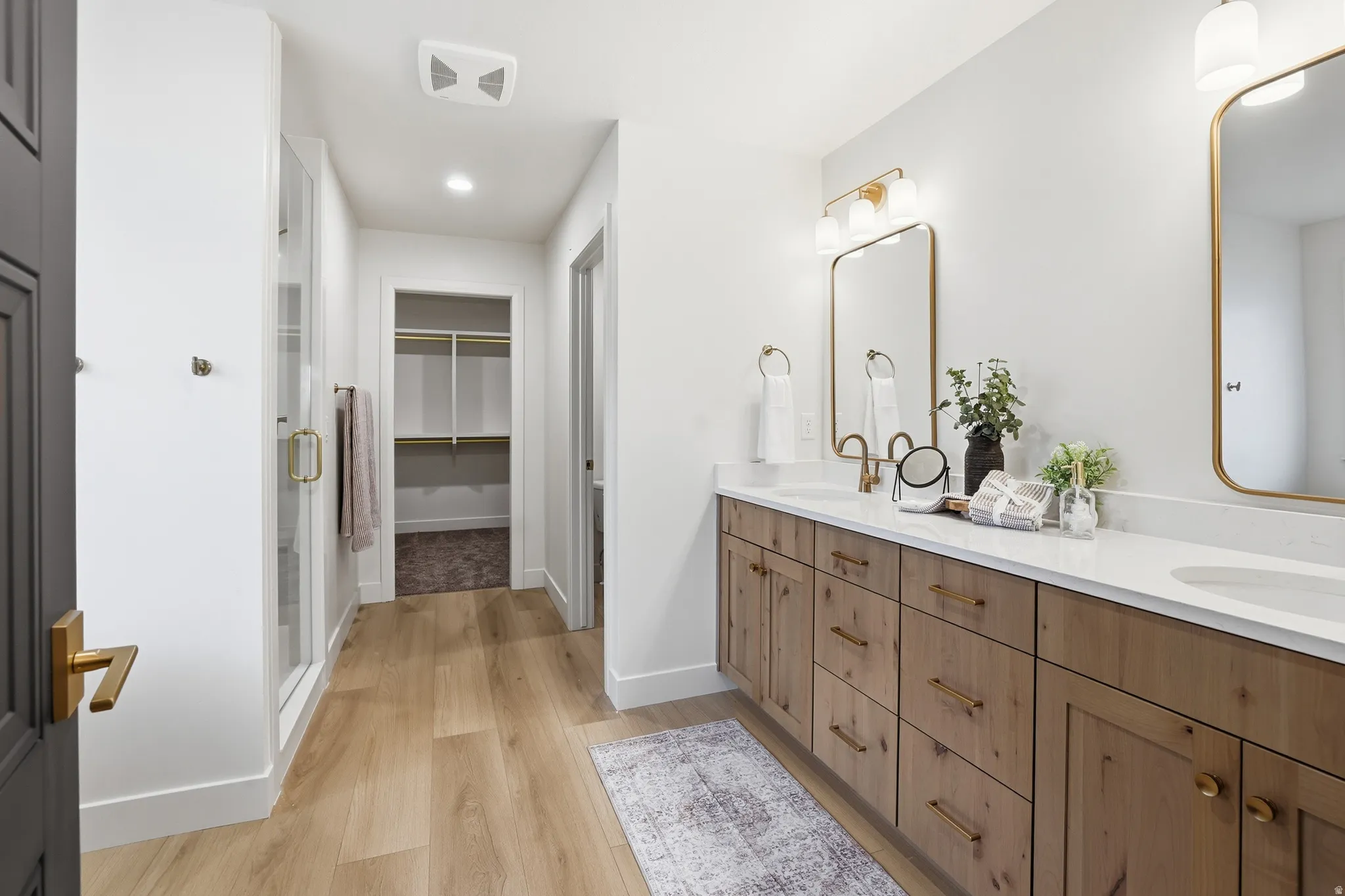 Dual vanity featuring a white quartz countertop, wood-finish cabinetry, and gold-tone hardware